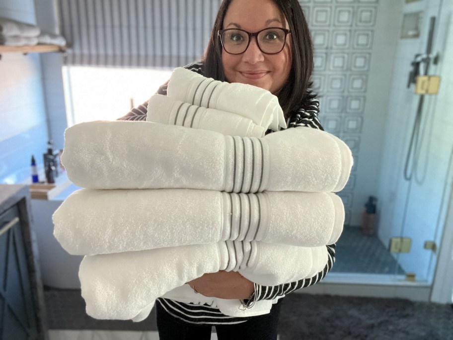 woman holding a stack of white towels in bathroom