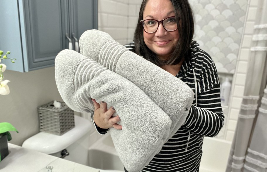 woman holding two bath towels in bathroom