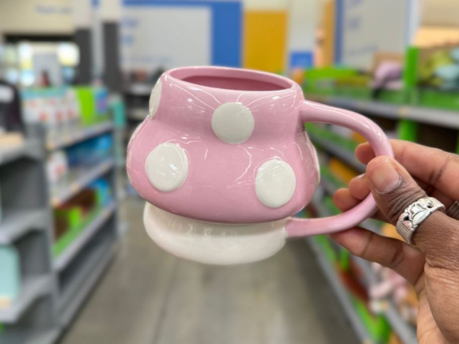 hand holding a pink and white mushroom coffee mug