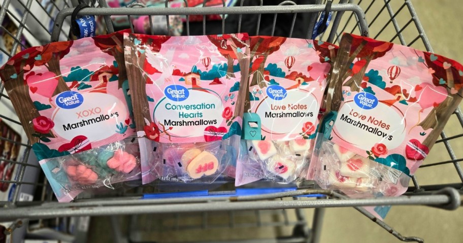 a Walmart shopping cart with the front section filled with 4 different bags of Valentine's themed marshmallows