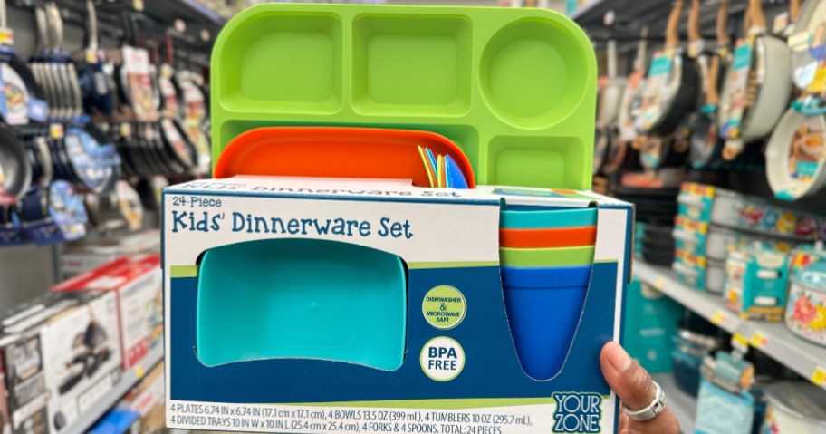 hand holding a kid's 24 pc dinnerware set that has brightly colored plates, cups and bowls
