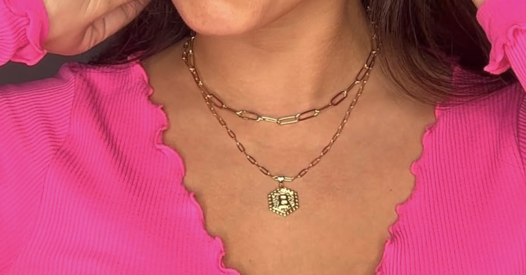 woman wearing charm necklace in pink shirt 