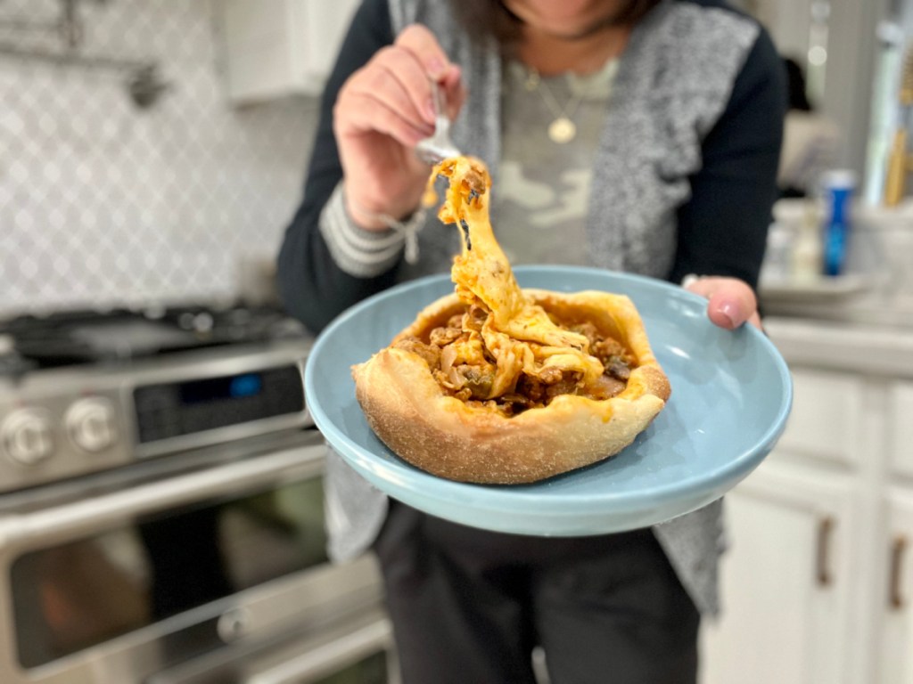 woman holding a cheesy pizza pot pie on a plate