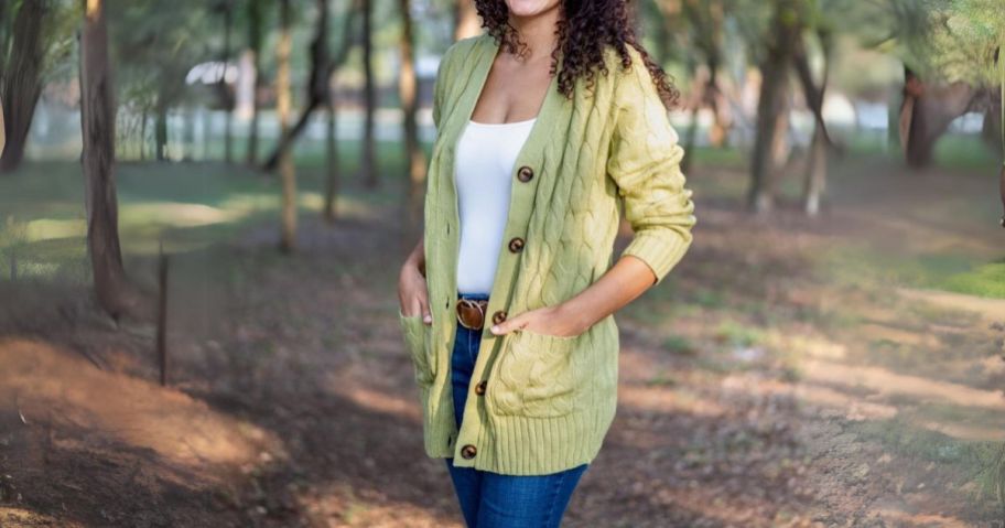woman standing outside wearing a light green cable knit cardigan sweater