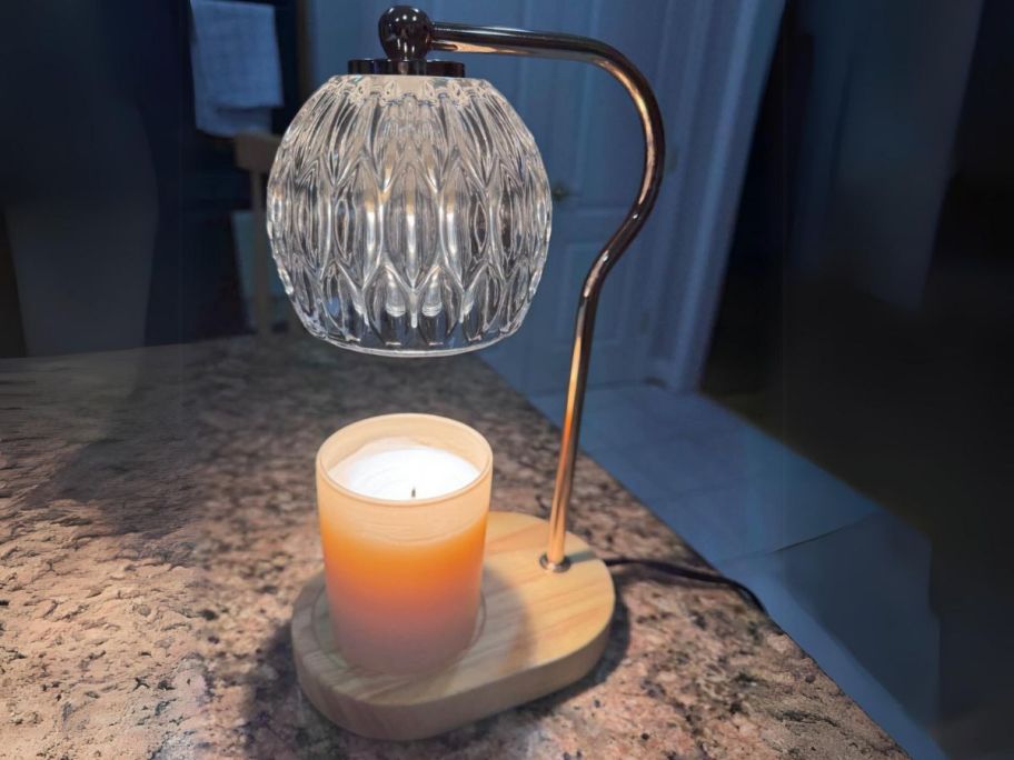 candle warmer lamp with a crystal shade, wood base and gold accents warming up a candle