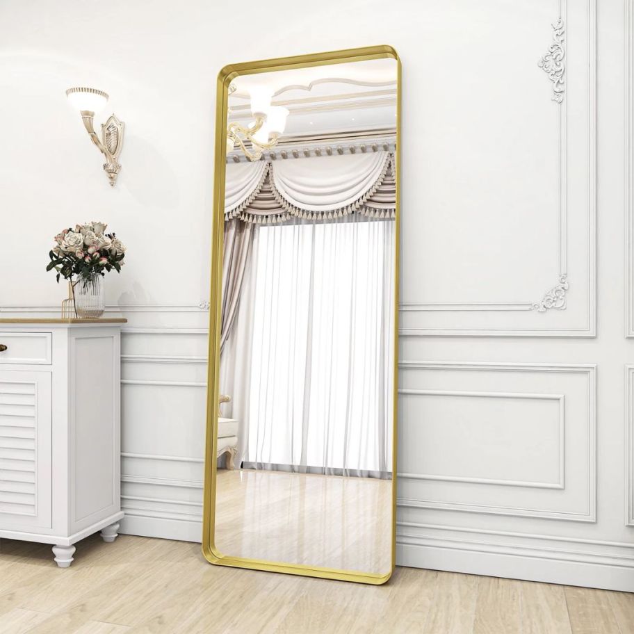 large rounded rectangle gold framed mirror against a bedroom wall