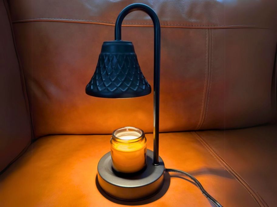 lit black candle warmer lamp with candle sitting on it