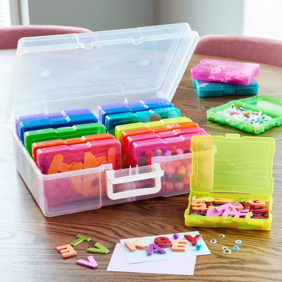 photo and craft storage box with different small containers, some on the table and open with craft supply items