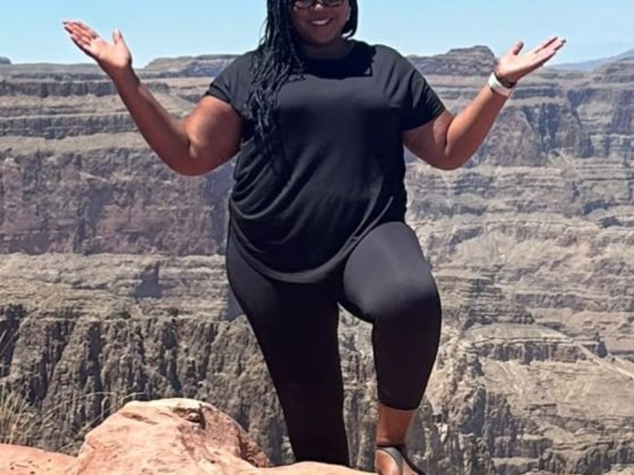 plus sized woman wearing a black t-shirt and leggings standing outside