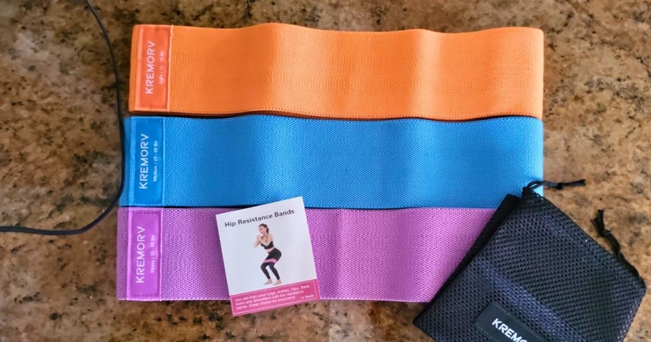 orange, blue and purple resistance bands with booklet and carry bag laying on counter