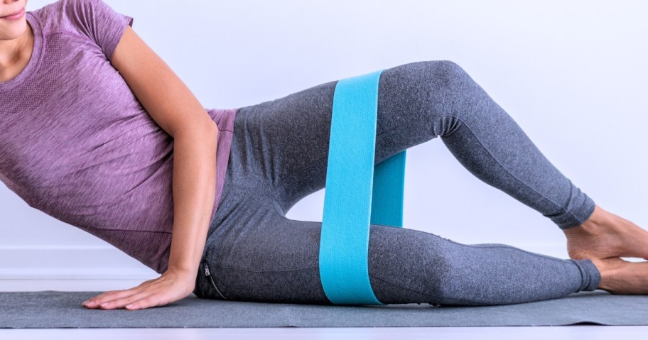 woman on a yoga mat using a blue resistance band