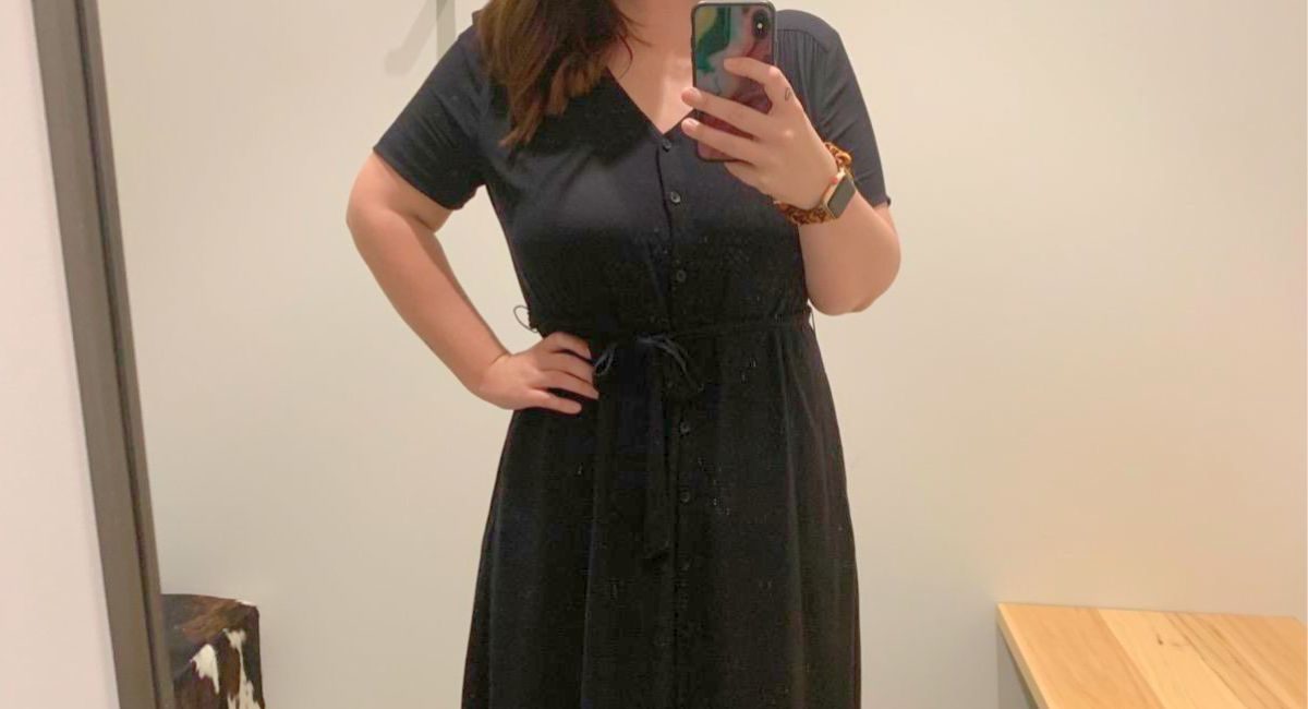 woman taking a selfie wearing a black midi style button down dress