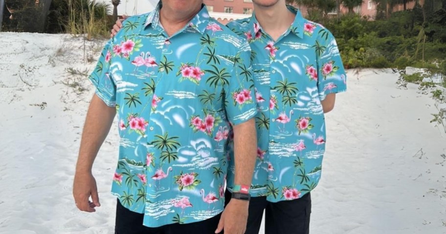 2 men wearing blue flamingo Hawaiian shirts standing on a beach