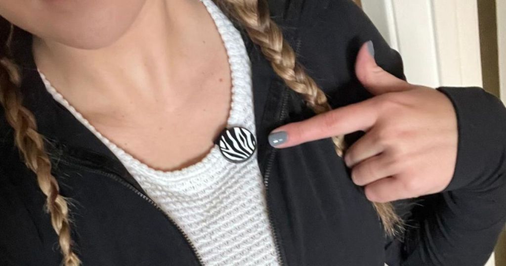 person wearing a SNAP CLIP remote in zebra print on her gym shirt and pointing to it