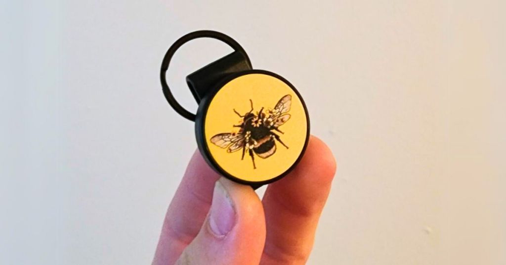 hand holding up a SNAP CLIP universal remote for mobile devices in yellow with a bumble bee on it