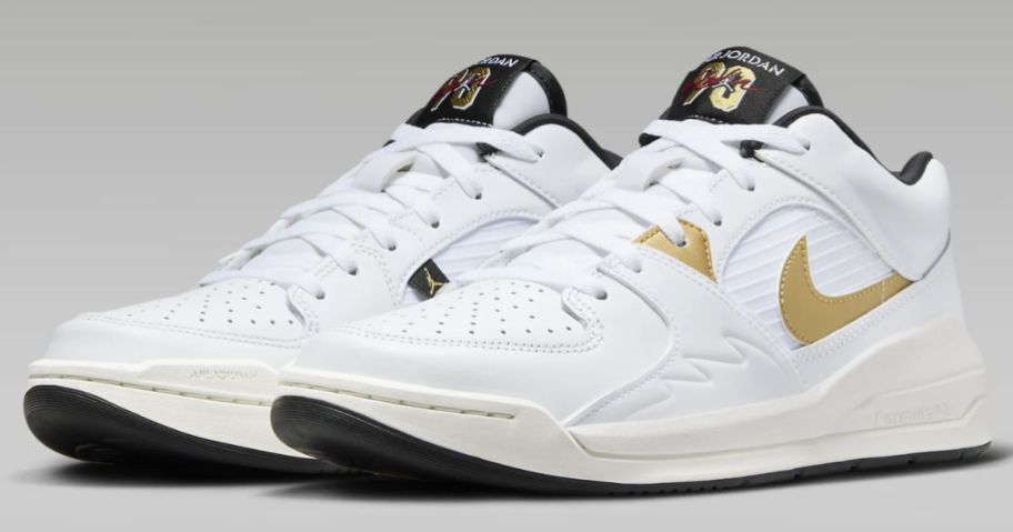 pair of white with gold and black accents men's Nike Jordan stadium shoes