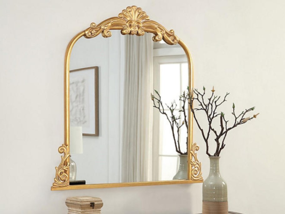 gold filagree wall mirror above a console table
