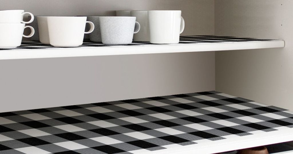pantry shelf with black and white shelf liner and cups and plates
