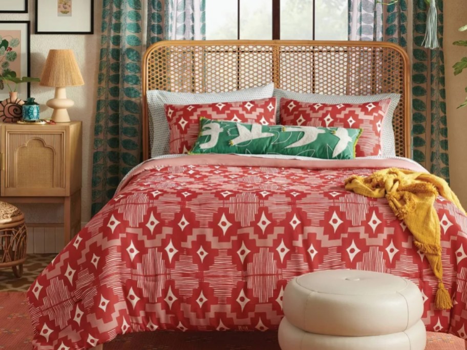 bed with a red and white geometric print comforter, shams and decorative green pillow