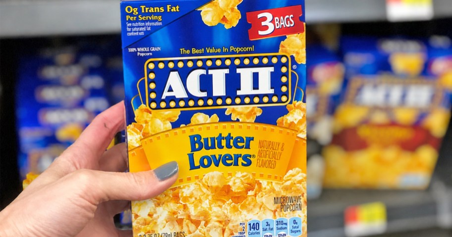 hand holding up a box of ACT II Microwave Popcorn in store aisle