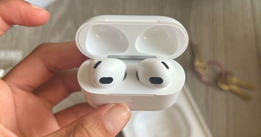 A person holding a Apple AirPods 3rd Generation with Lightning Charging Case