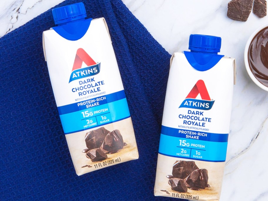 two Atkins Dark Chocolate Royale Protein Shakes on a kitchen towel on counter