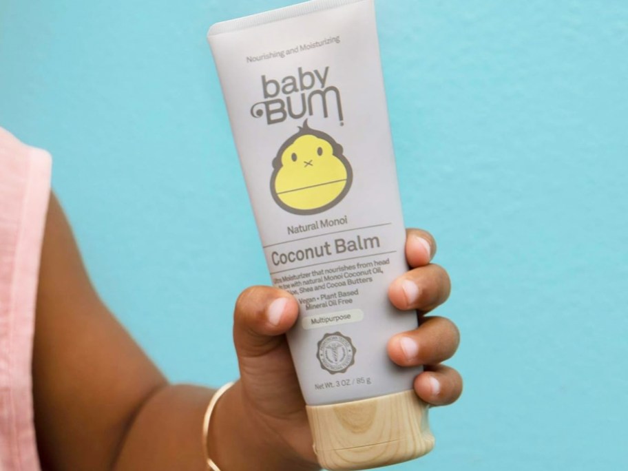 child holding a tube of Baby Bum Monoi Coconut Baby Balm