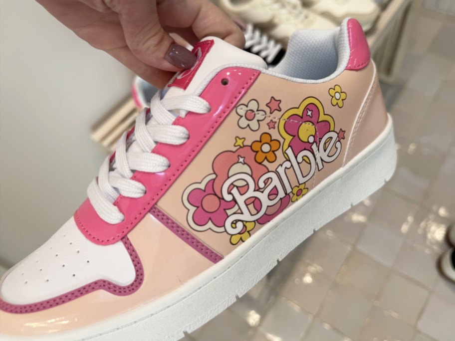 hand holding a pink floral print sneaker that says barbie