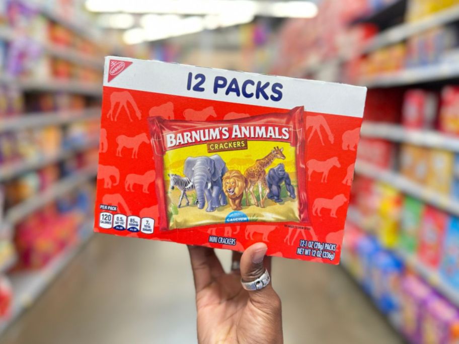 A hand holding a Barnum's Original Animal Crackers 12 Pack box