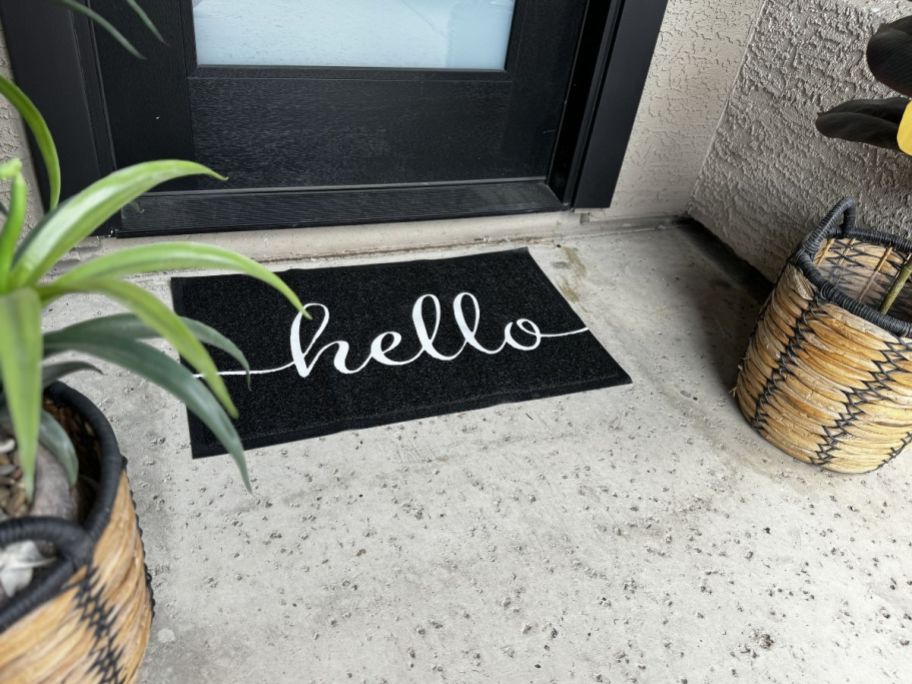 A doormat in front of a door that says "hello" 