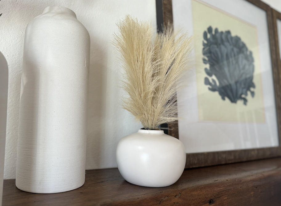 pampas grass in white vase on wood mantle