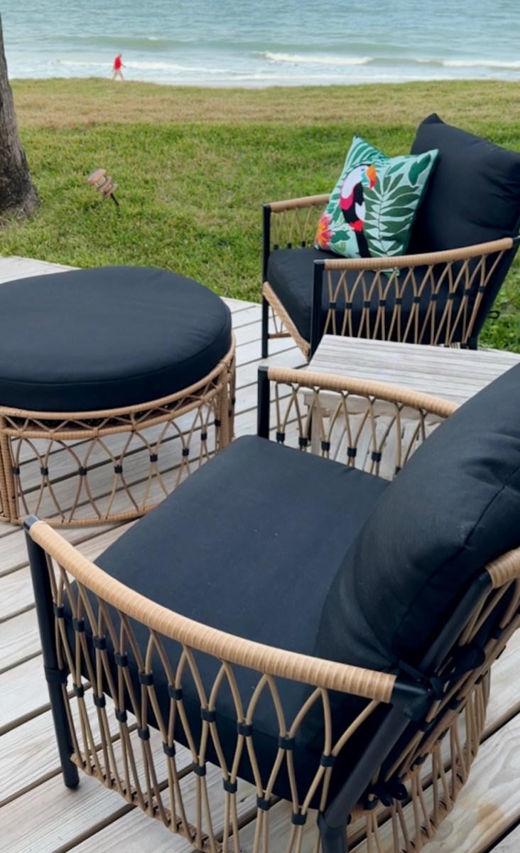black and wicket outdoor chairs with bird pillow sitting on patio deck outside