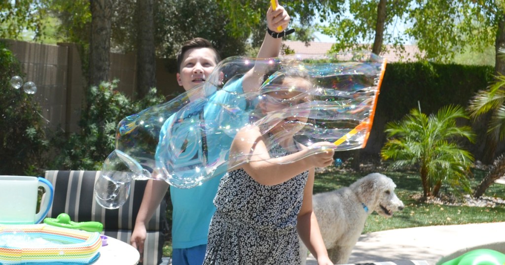 two kids making large bubbles with bubble wands