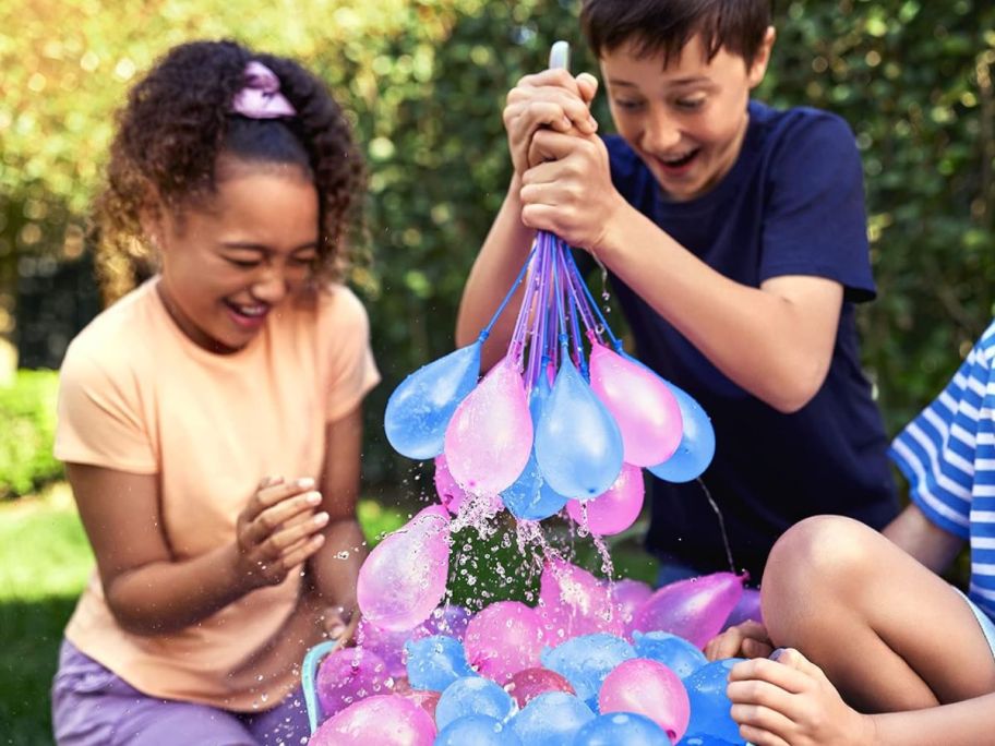 kids playing with blue and pink water balloons