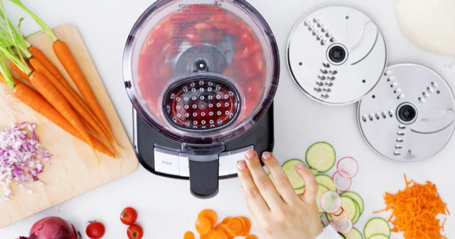 person pressing button on black and silver food processor 