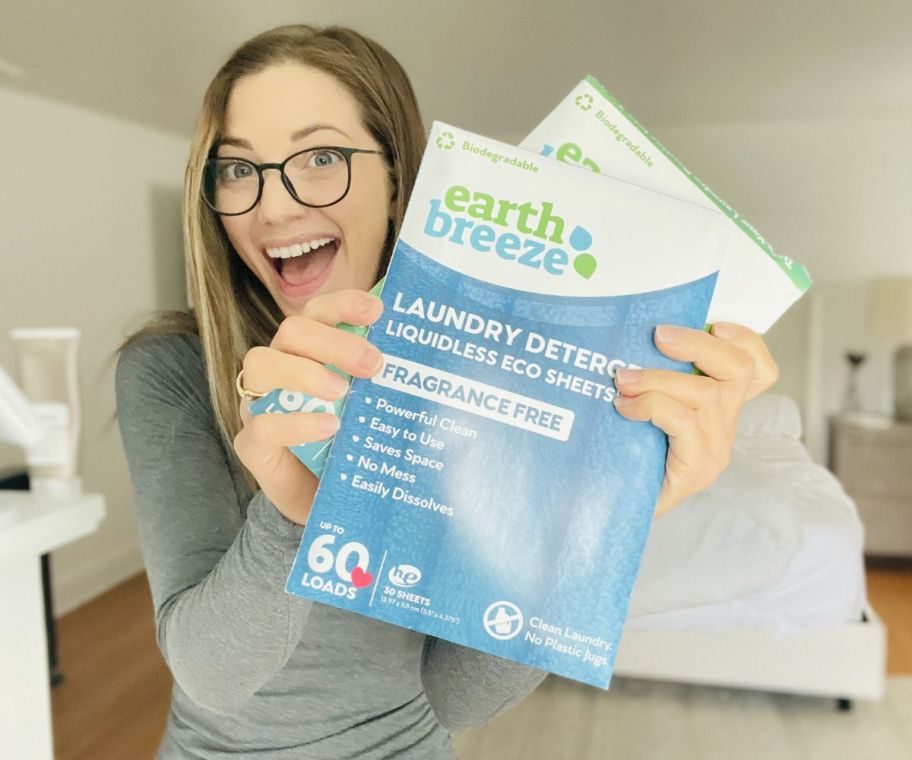 a woman holding 2 packages of earth breeze laundry det in scented and unscented.