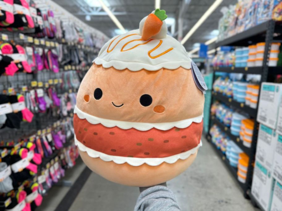 A hand holding an Easter Squishmallow Carrot Cake at Walmart