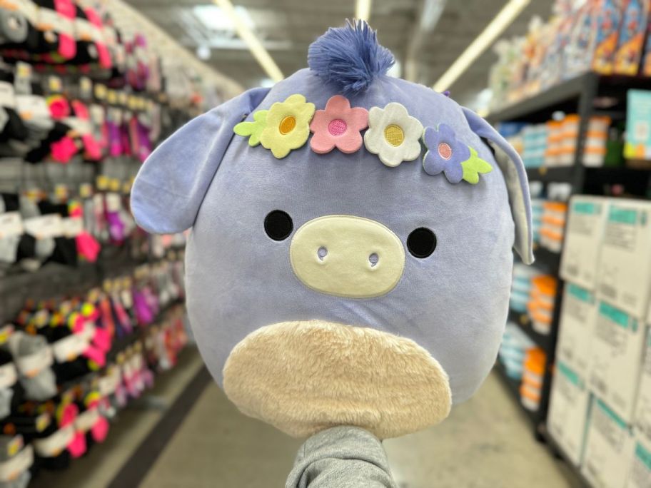 A hand holding an Easter Squishmallow Donkey at Walmart