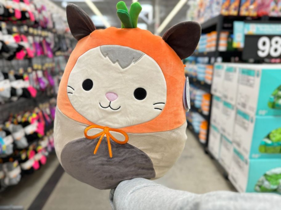 A hand holding an Easter Squishmallow Possum at Walmart