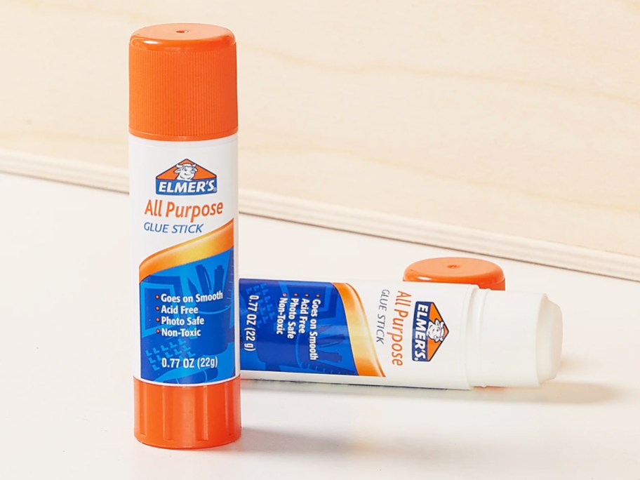 two white and blue glue sticks with orange caps