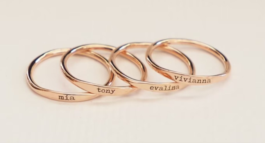 four rose gold rings with names on them
