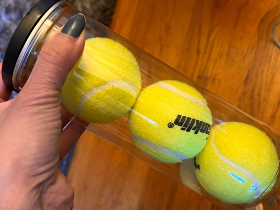 Hand holding a canister with 3 Franklin Tennis Balls inside