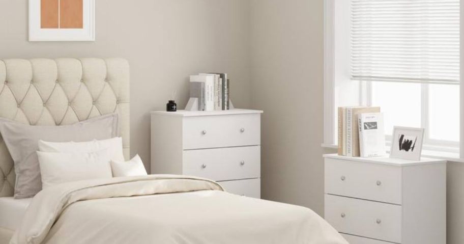 2 white dressers in bedroom by bed