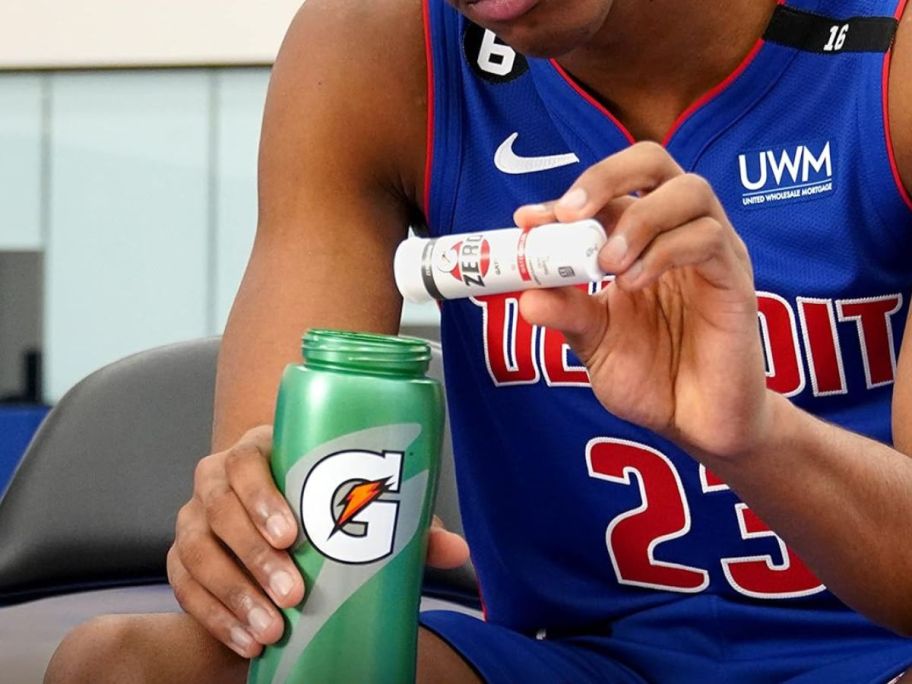 An athlete adding Gatorade Zero Tablets to their water bottle