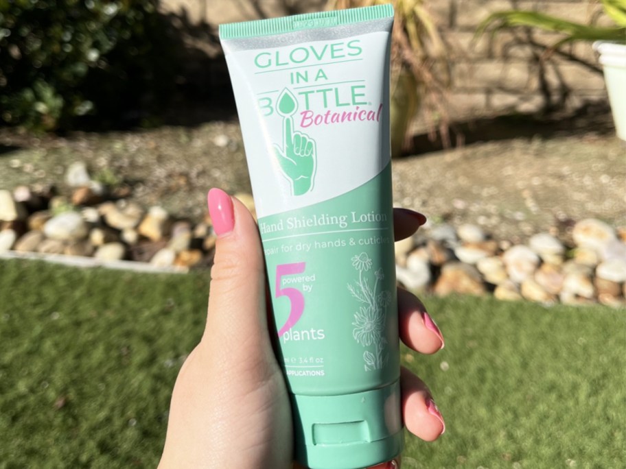 hand holding a tube of Gloves in a Bottle Botanical lotion