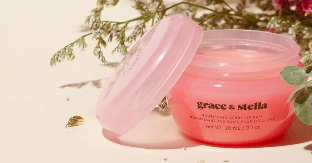 opened pink jar of Grace & Stella lip mask with flowers behind it