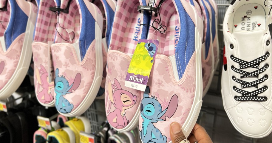 hand touching a pair of pink lilo & stitch sneakers in store