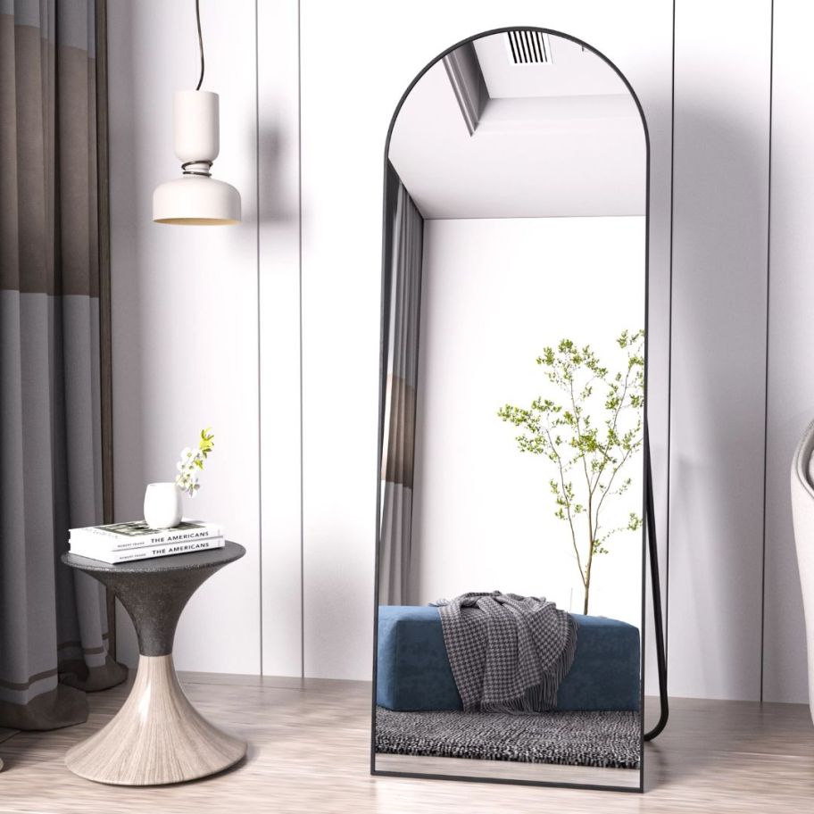 large black floor length arched mirror against a wall