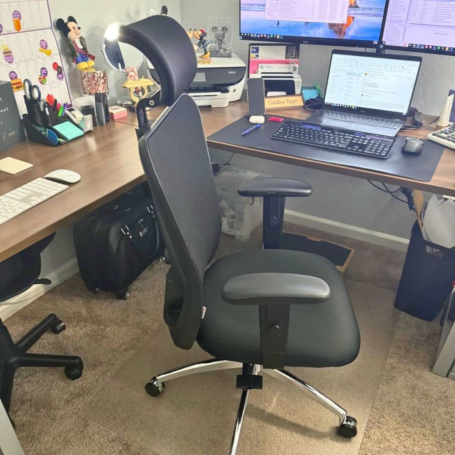 black mesh office chair with headrest and armrests sitting next to a desk