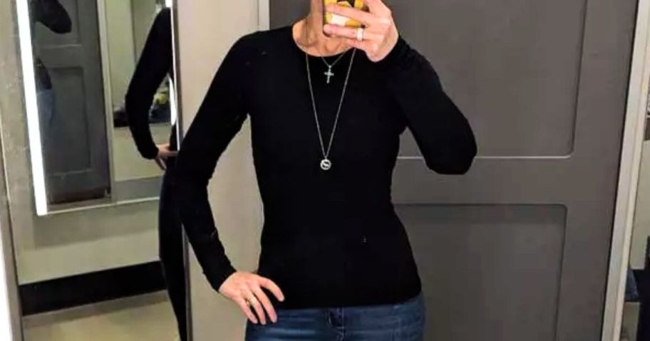 woman wearing a black long sleeve fitted shirt taking a selfie